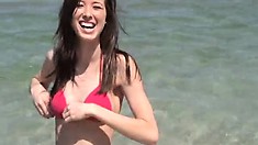 Gorgeous brunette teen in a red bikini heads to chill at the beach